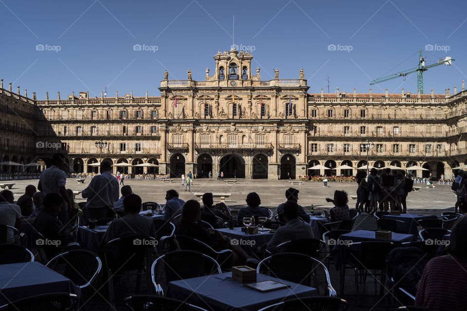 terraza llena de gente en la plaza mayor de Salamanca, vemos detrás la preciosa fachada de un edificio clásico, hoy ayuntamiento de Salamanca
