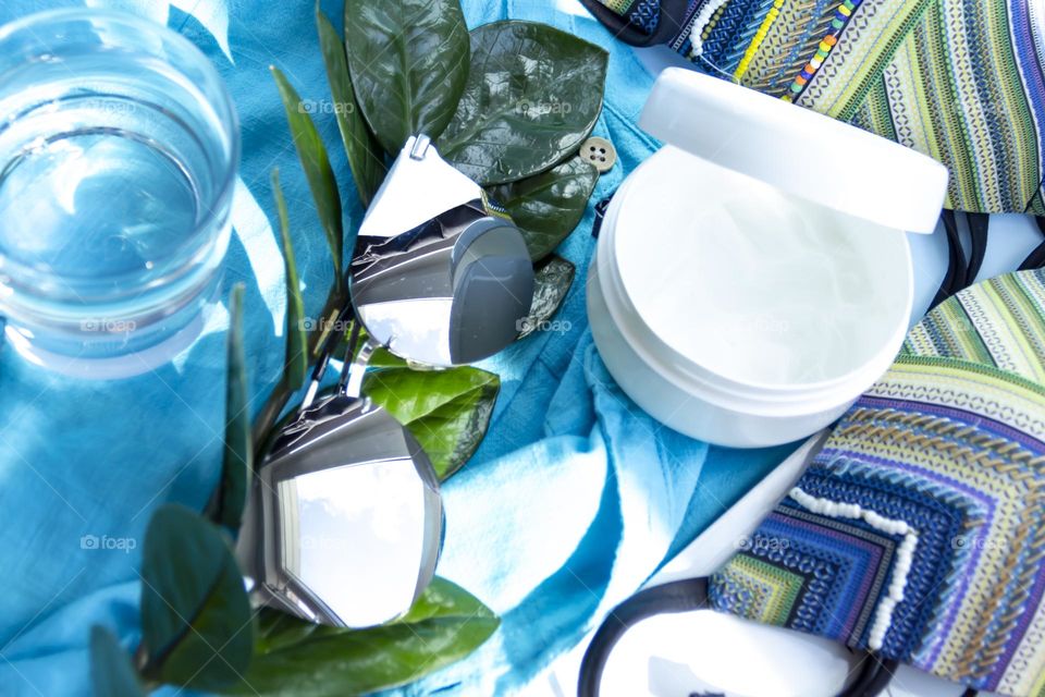 Items prepared for travel.  Swimsuit, shirt, skin cream and sunglasses on a blue background.