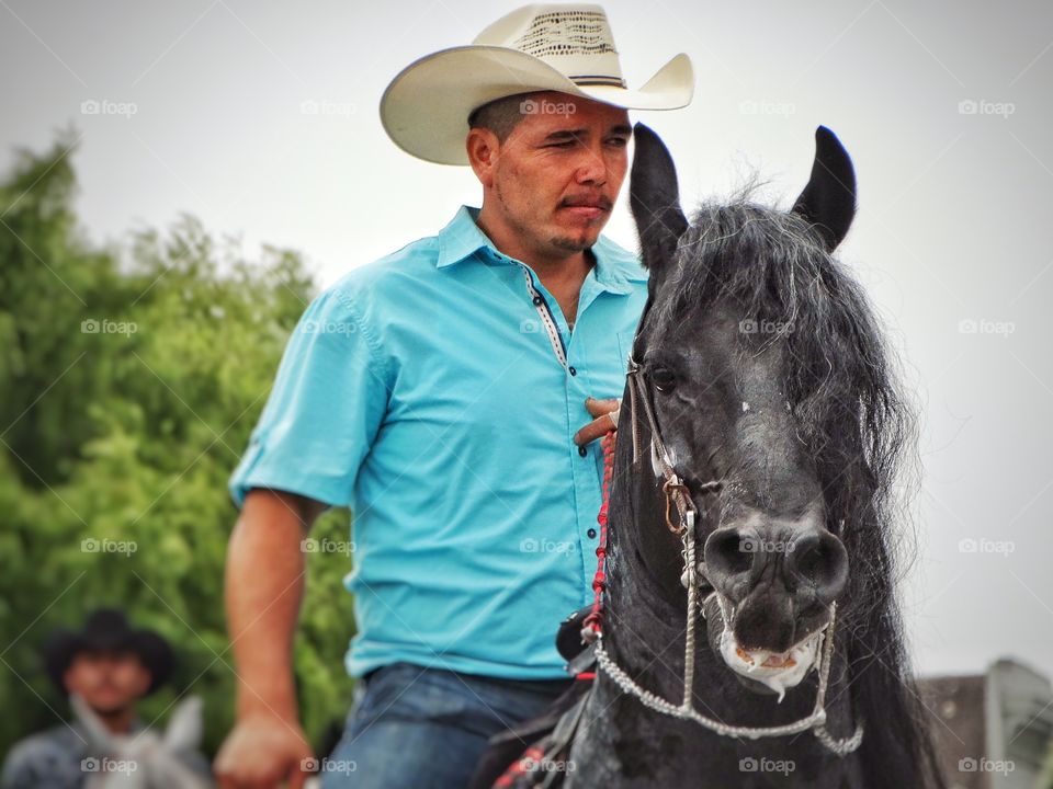 Latino Cowboy. Cowboy Riding A Black Stallion
