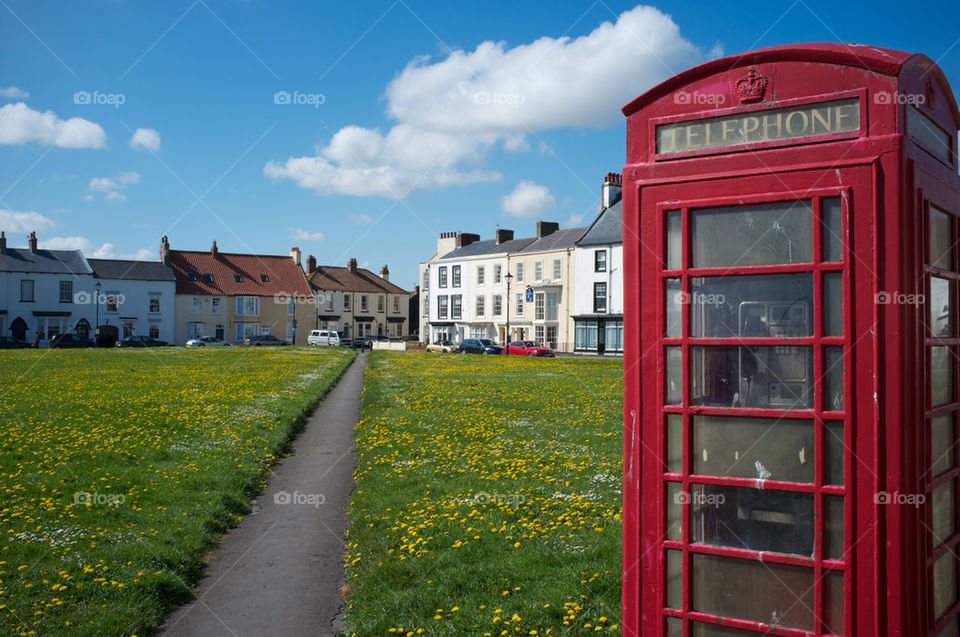 A RED TELEPHONE BOX STANDS ON THE EDGE OF A BEAUTIFUL ENGLISH VILLAGE