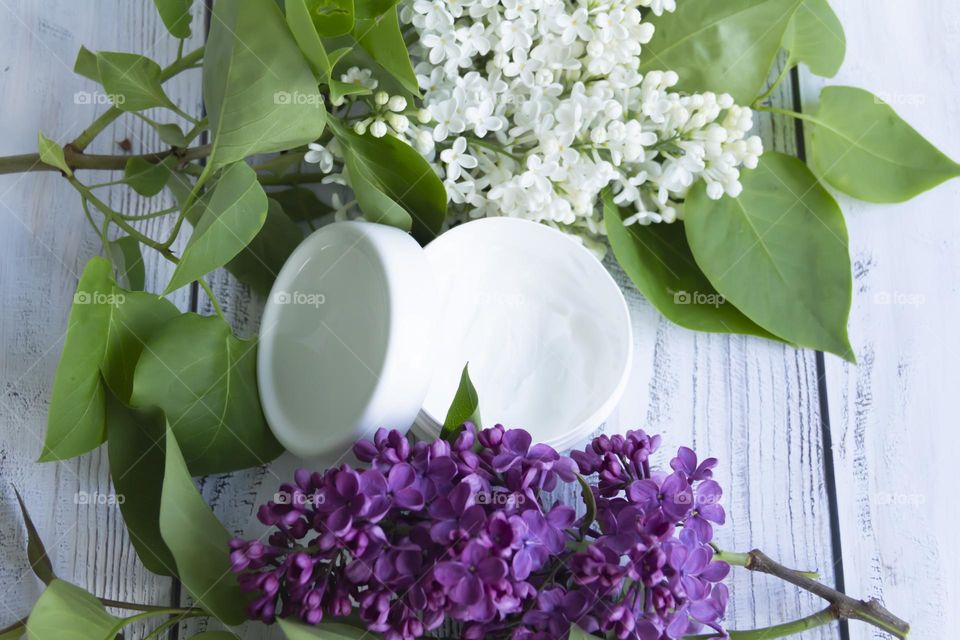 Jars with cosmetic products, beauty cosmetics in a white jar with cream and water with fragrant flowers.