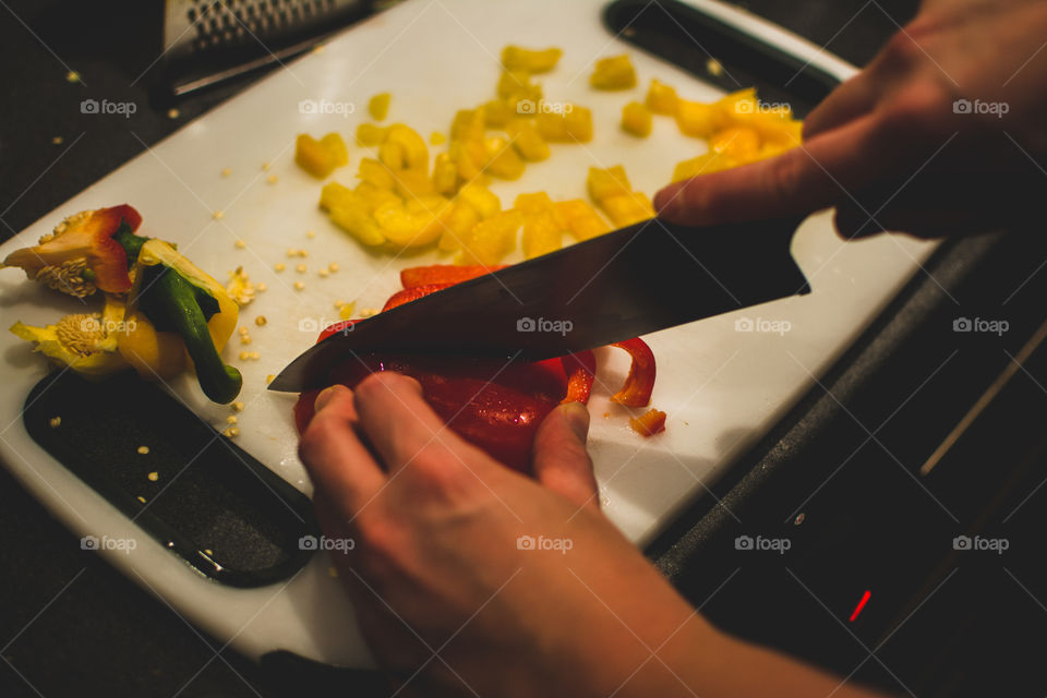 Close-up of person's hand chopping bell pepper