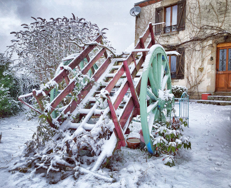 A picturesque snow covered cart outside a traditional farmhouse in rural France - January 2019