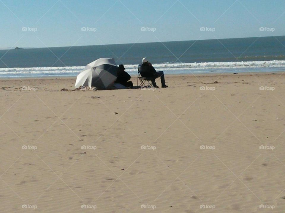 People near the sea under umbrella