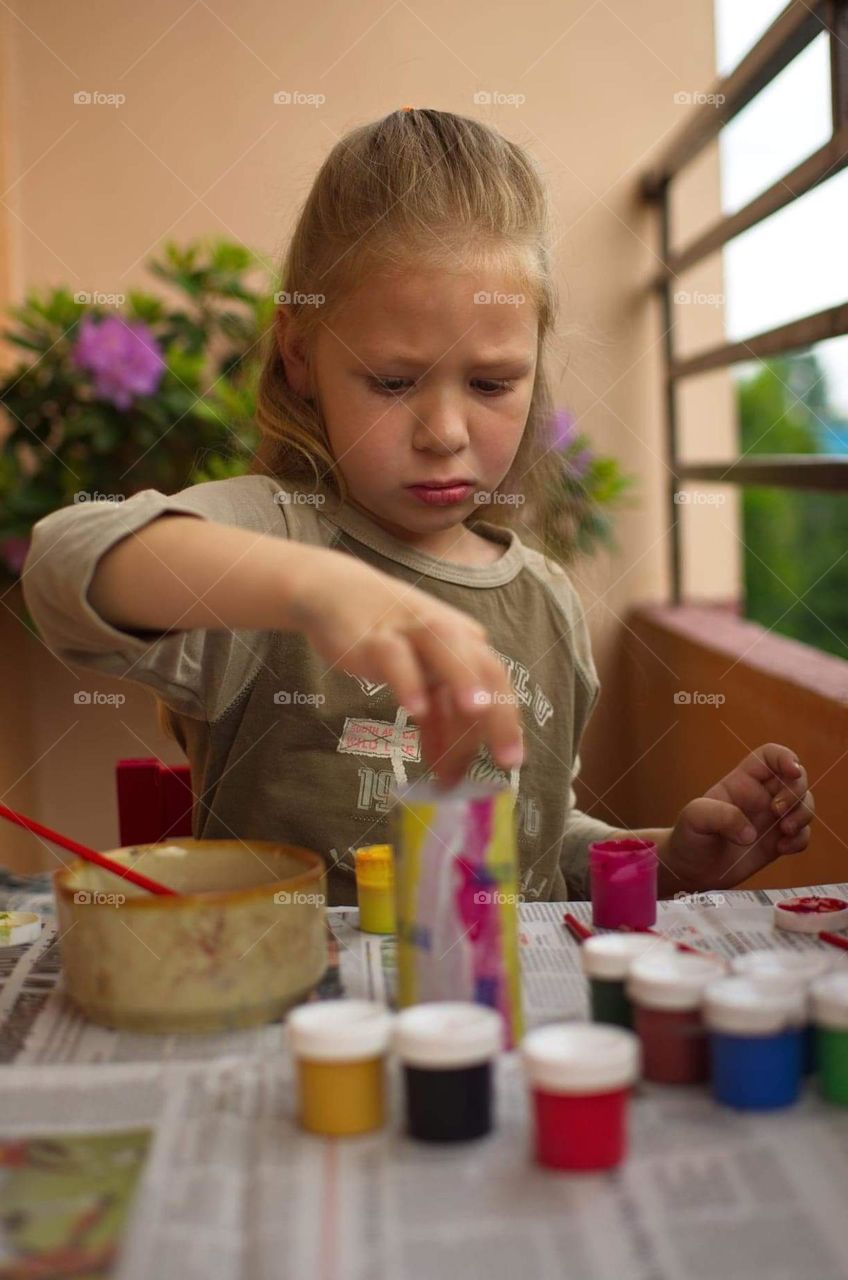 A girl painting with acrylic paints.