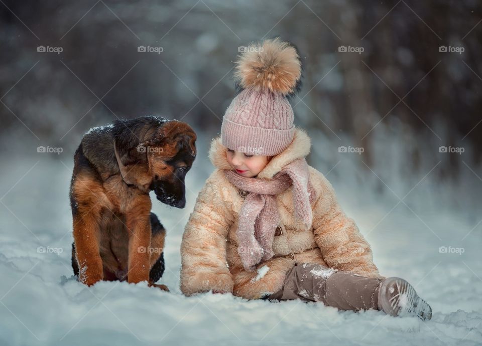 Little girl portrait with German shepherd puppy at winter