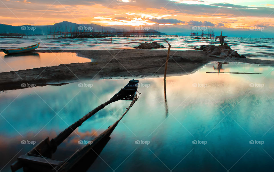 View of old canoe in sea during sunset