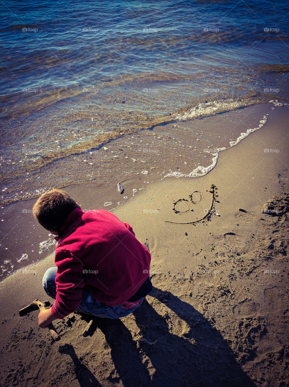 Child drawing faces FELICIE in the sand of the autumn sea, in the nicest sandy Forte dei Marmi.