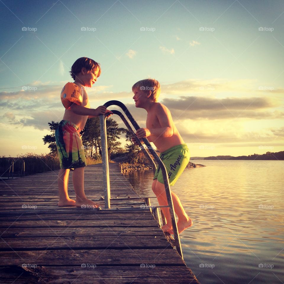 Two boy on pier near lake
