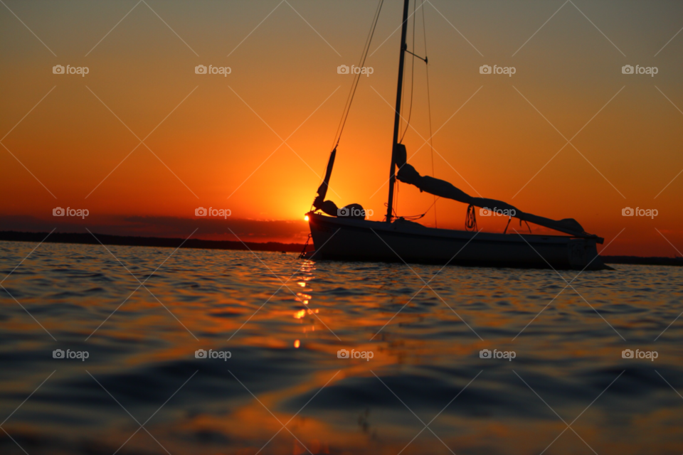 Silhouette of sailboat on sea at sunset