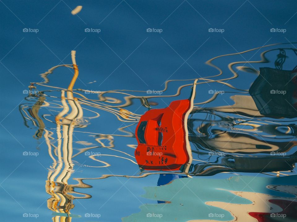 Colorful water reflection of a fishing boat at a marina in Babakale, Canakkale, Turkey.