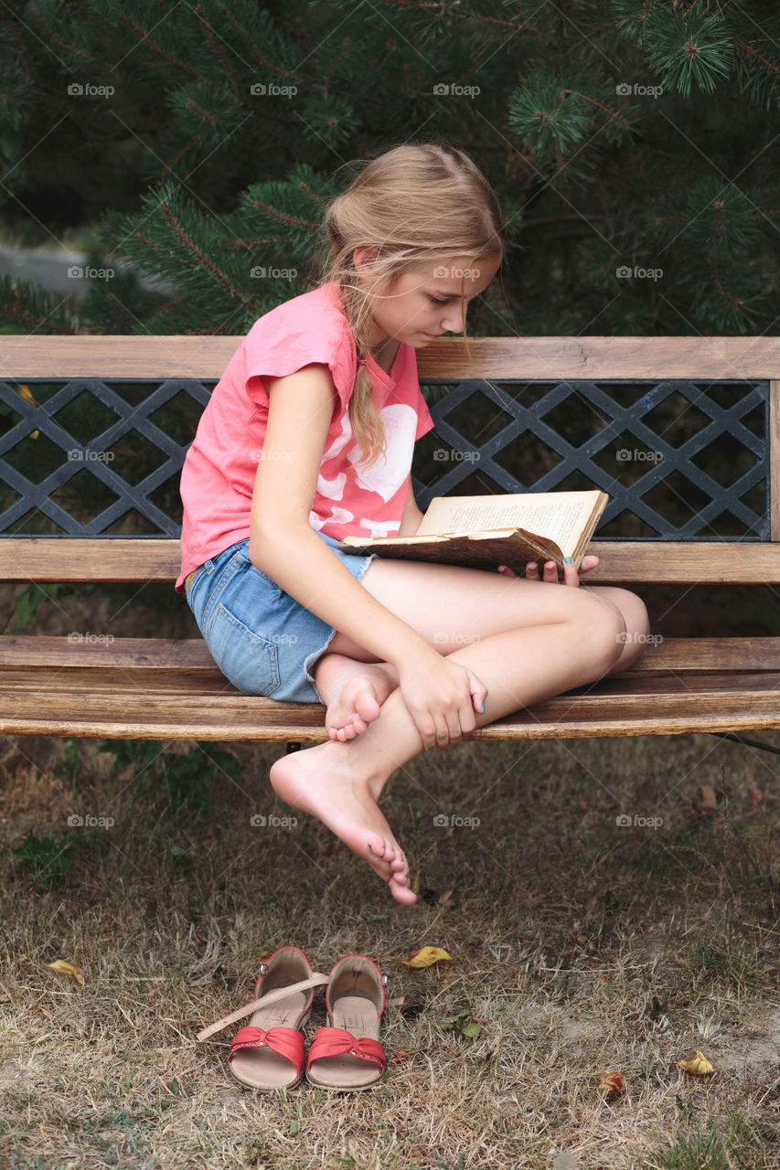 Girl sitting on bench reading book