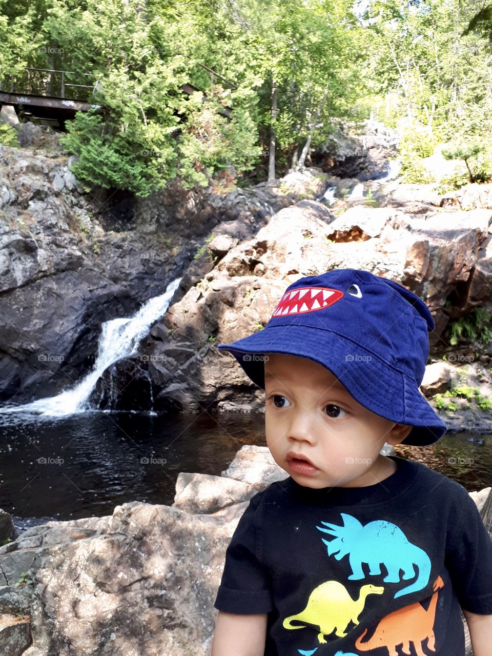 Toddler standing in front of a waterfall scenary
