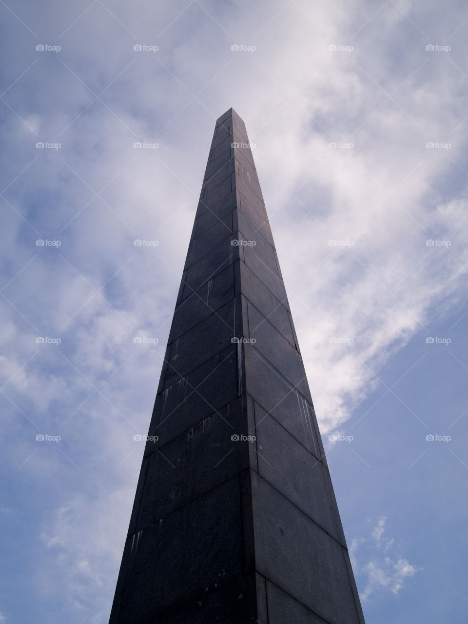 gray concrete cone-shaped monument under a blue sky with white clouds