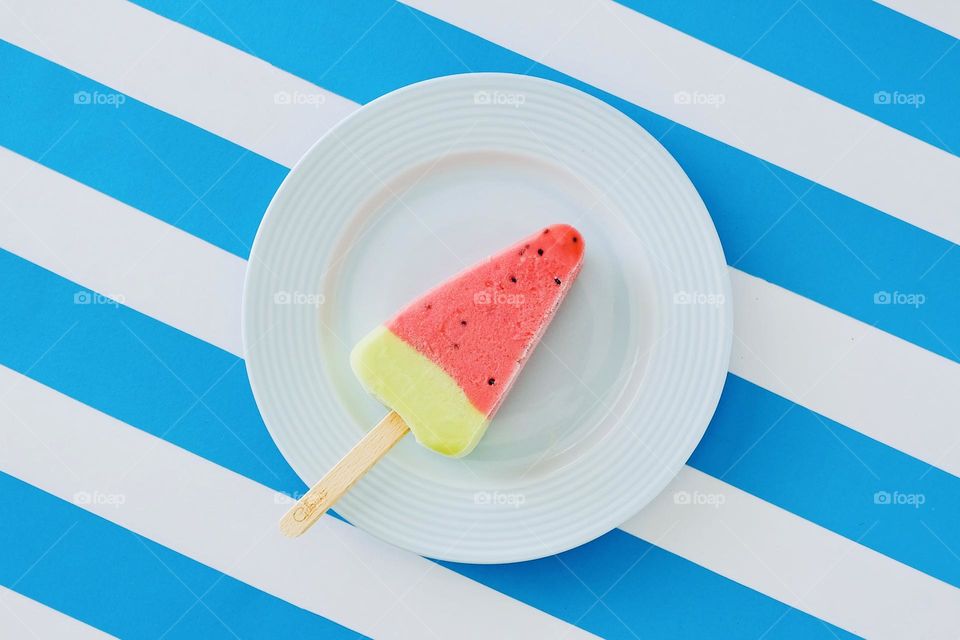 Directly above view of watermelon ice cream on plate isolated on striped background. 