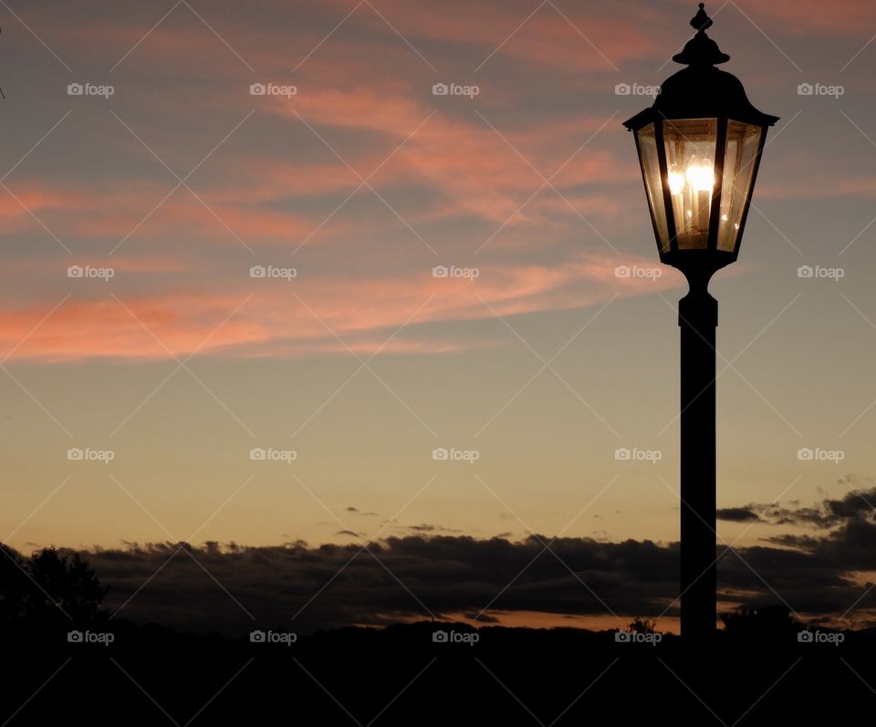 Beautiful sunset with lamppost and mountains in background. 