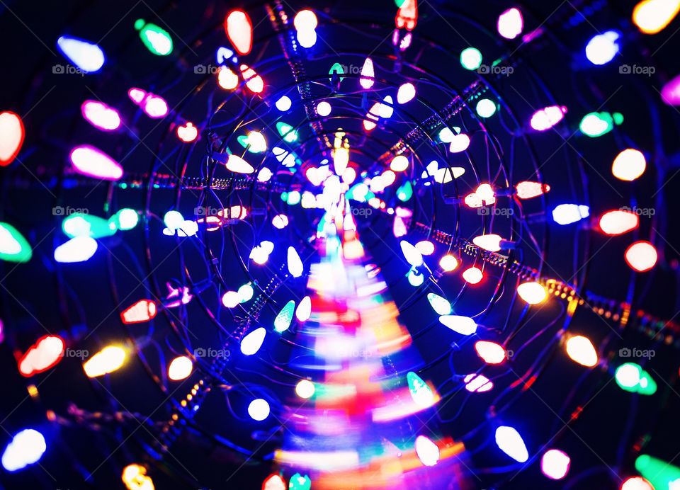 Metal Christmas tree, Christmas  lights from the inside center of the tree looking up. Multi colored.