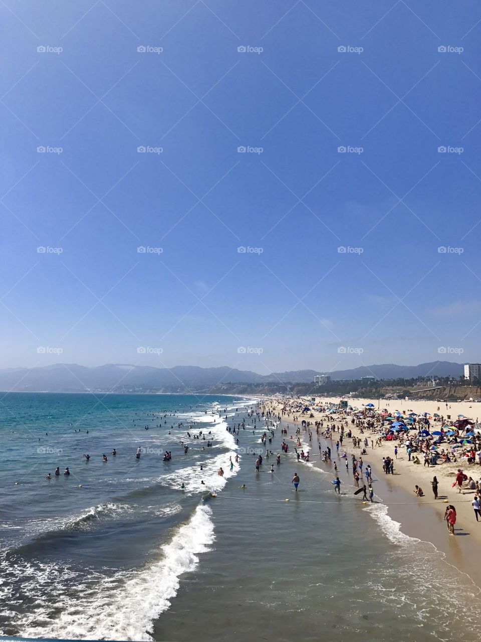 Crowded Downtown Santa Monica beach at midday. 
