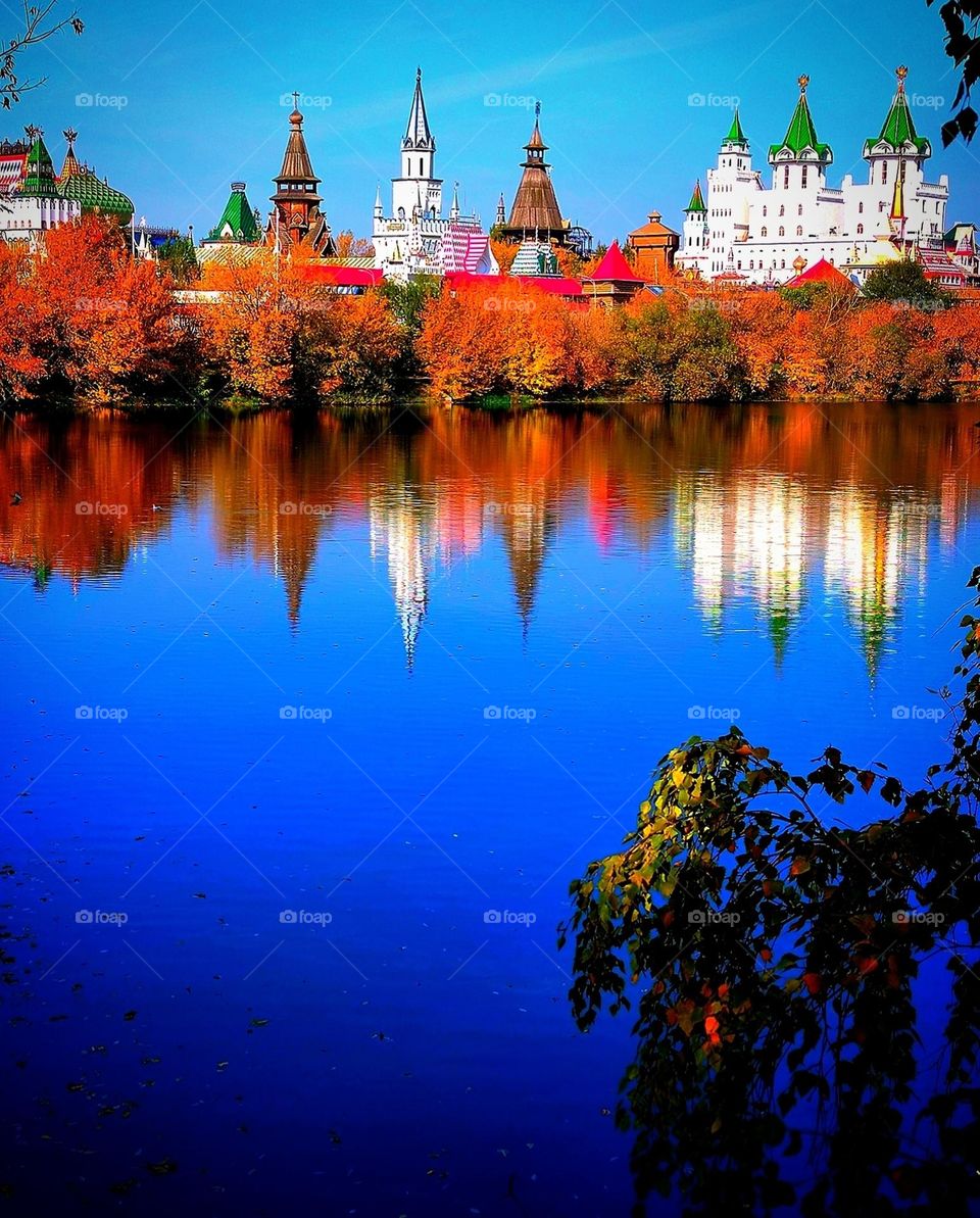 Autumn landscape. Reflection of autumn trees and towers in water