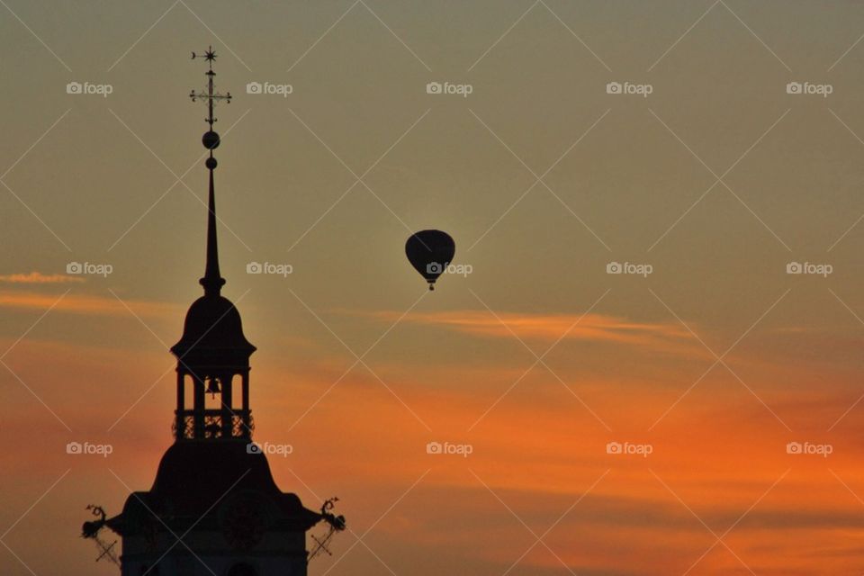 Silhouette of bell tower with weather vane against dramatic sky