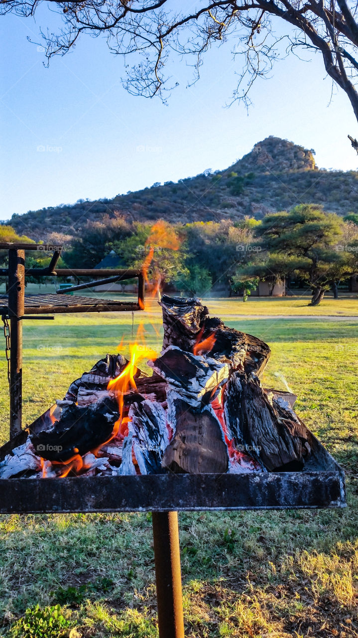 Fire burning as the sun goes down with a mountain top in the background