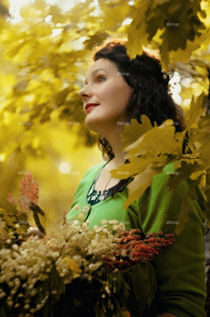 portrait of a mother in a green forest with a basket of flowers