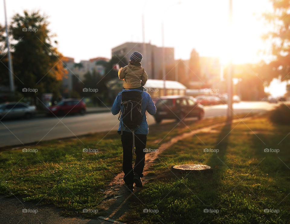 Father and son hiking together through the autumn city in the evening during the sunset time 