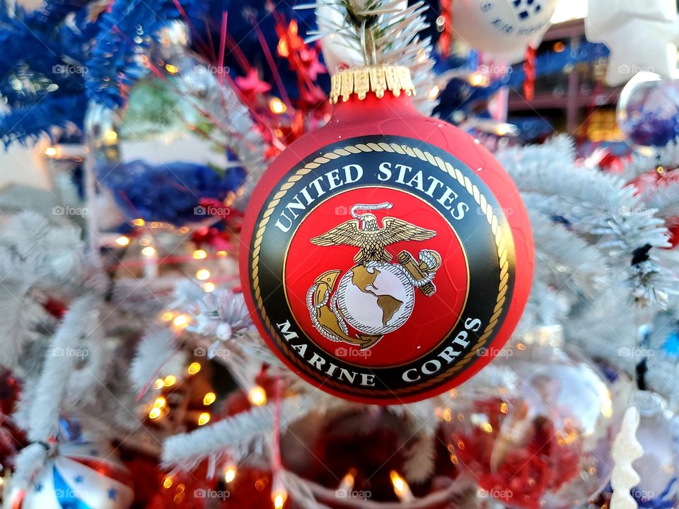 Red United States Marine Corps Christmas ornament hanging on a red, white and blue Christmas tree honoring all branches of service