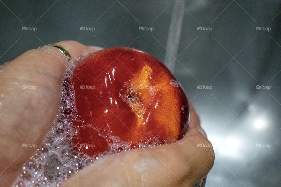 Washing orange nectarine fruit with soap and water to clean