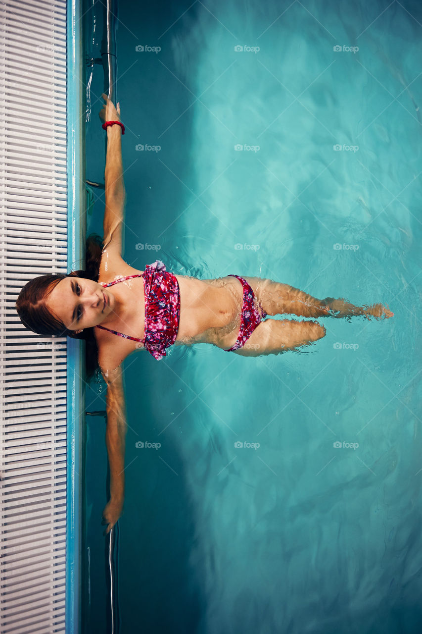 Young woman swimming and relaxing in swimming pool. Candid people, real moments, authentic situations