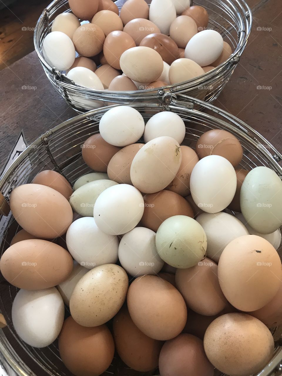 A basket of freshly hatched eggs, ready for purchase on the farm. Different colored shells all together. 