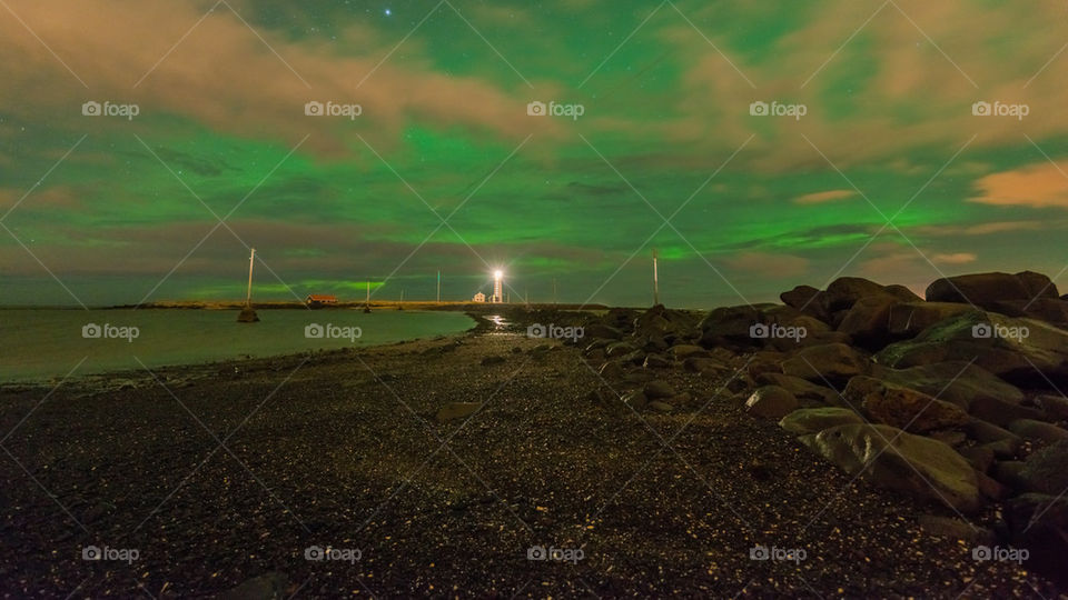 Meteor shower with northern lights and lighthouse