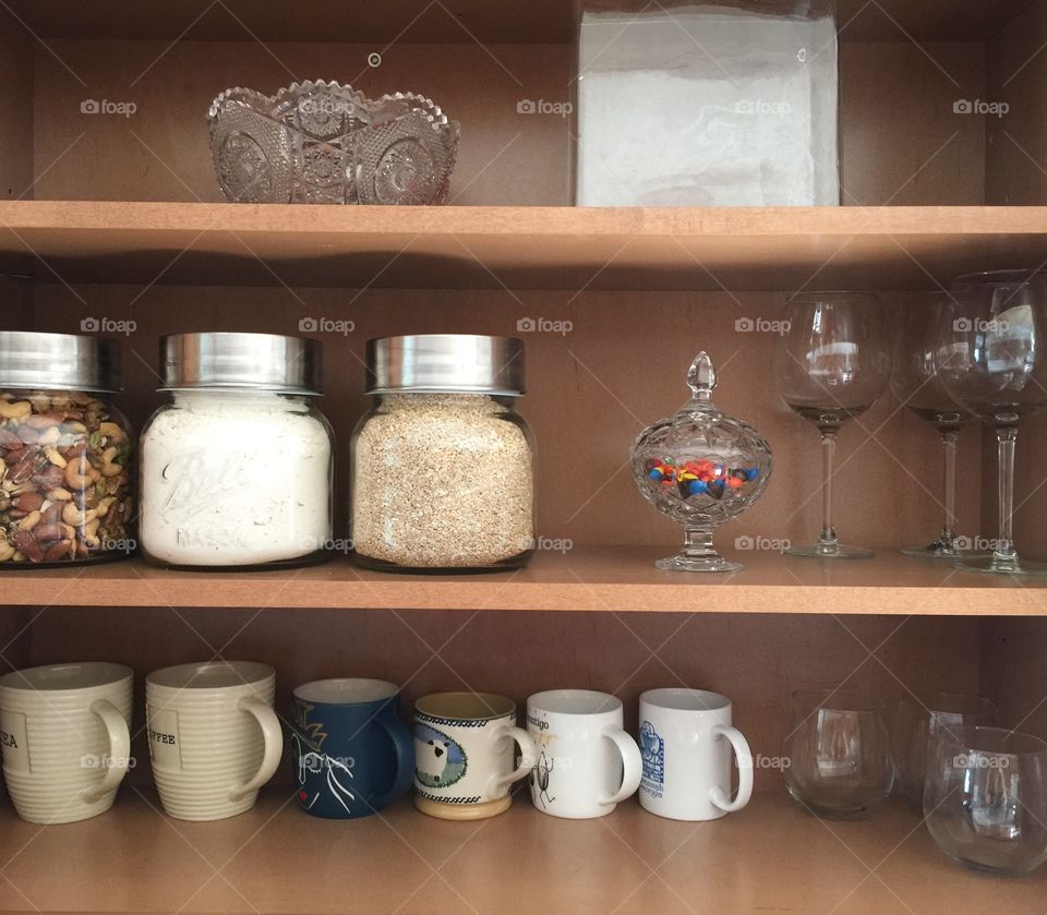Organized shelves in kitchen with coffee mugs, glass storage, crystal vases, candy dish, wine glasses