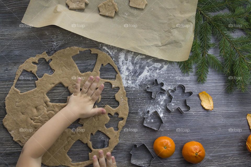 Christmas, gingerbread cookies on a wooden table sprinkled with flour, with tangerines and a green Christmas tree.