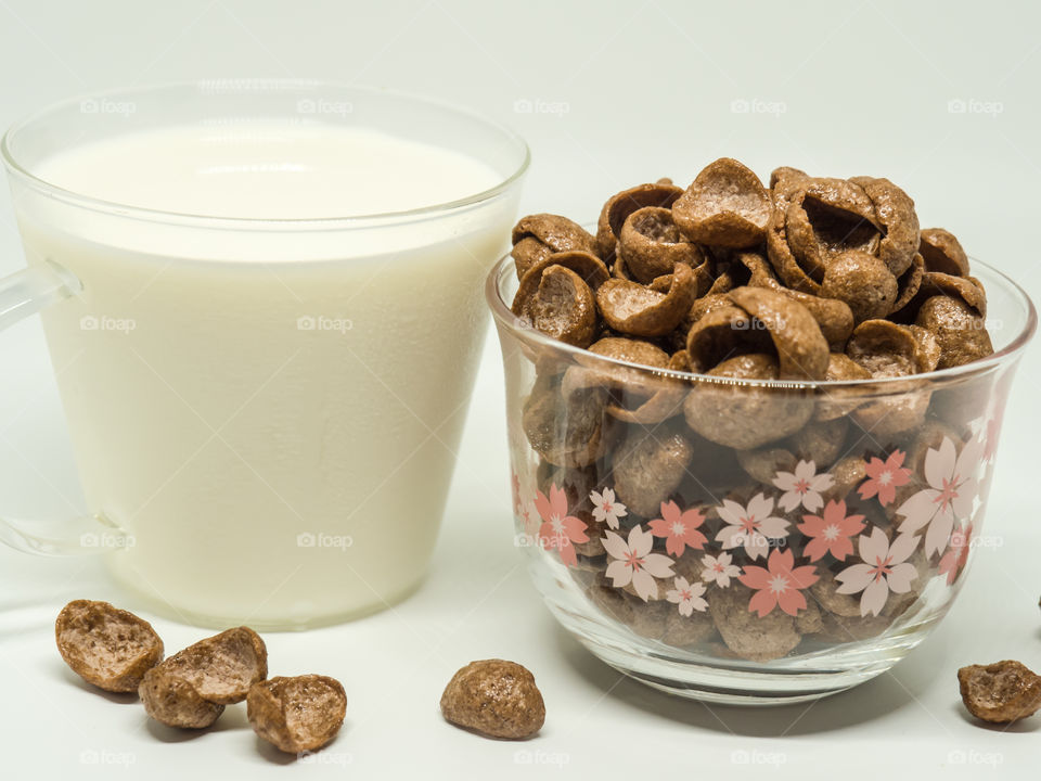 Chocolate breakfast cereal and a cap of milk.