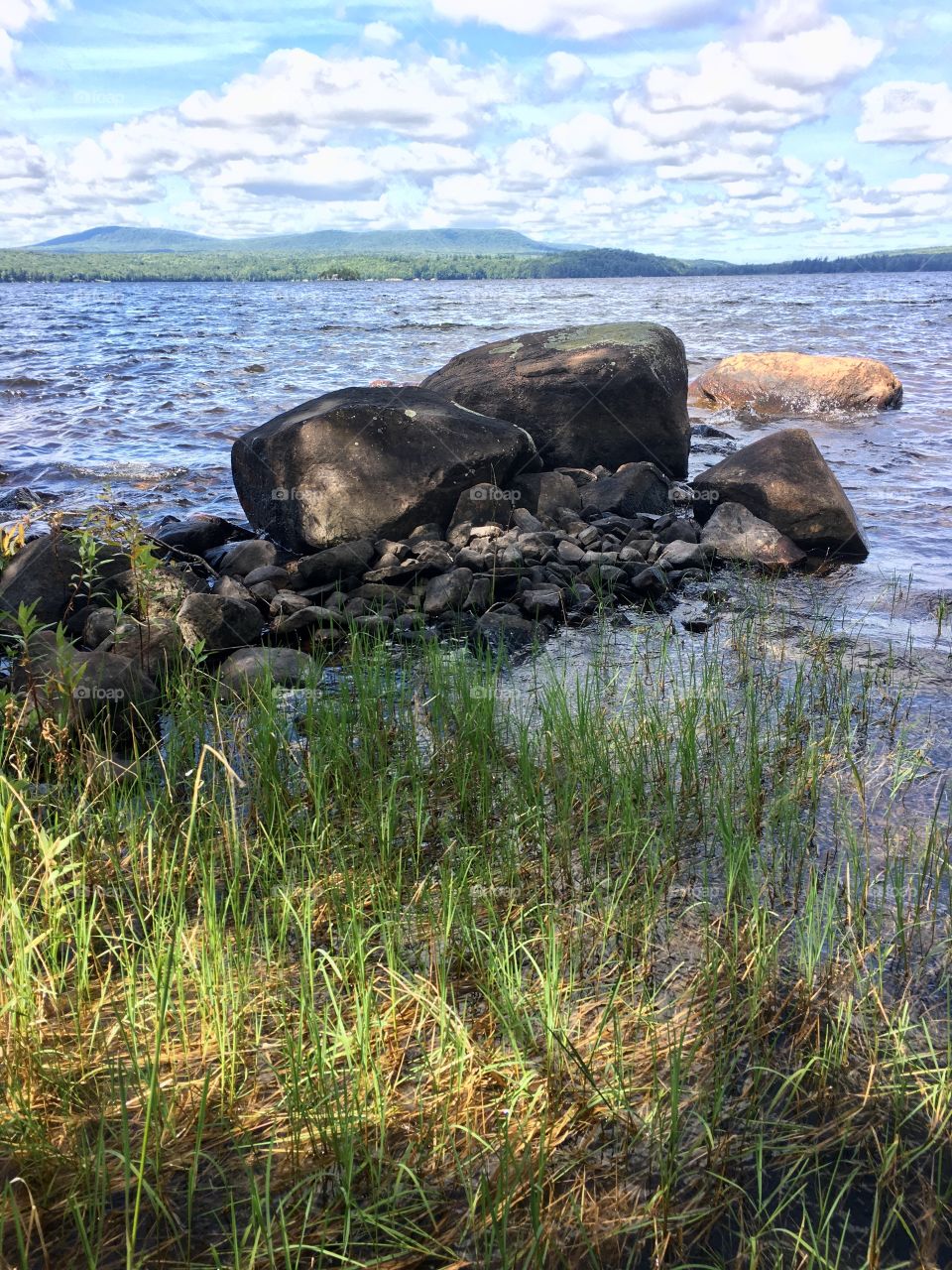 Lakeshore; large rocks boulders and lake grasses on Adirondack mountain lake 