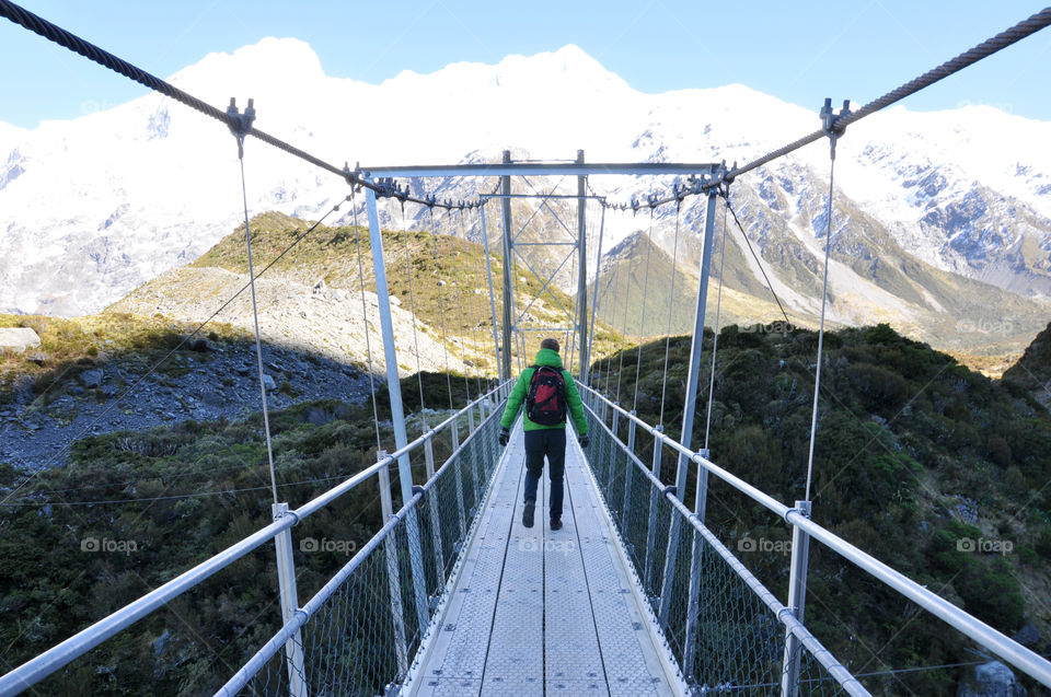 Man crossing a bridge in high mountains