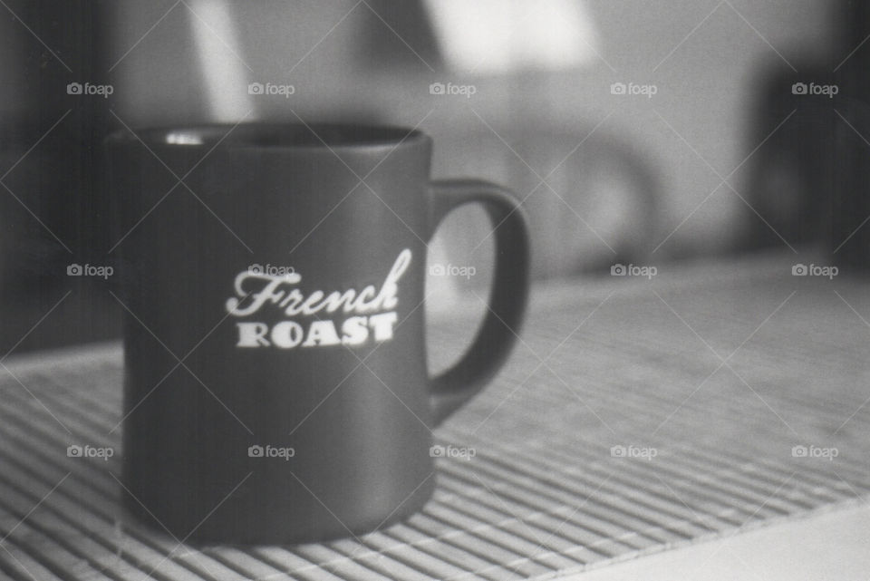 Film black and white photo of a black mug with French roast written on it 