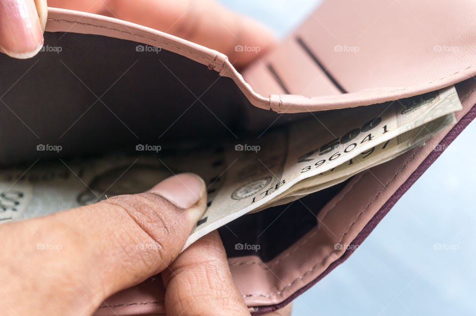 Businesswoman putting or taking out or paying Indian rupee banknotes from leather wallet. Isolated white background. Earning crisis growth bribe corruption bankrupt concept. Selective focus Close-up
