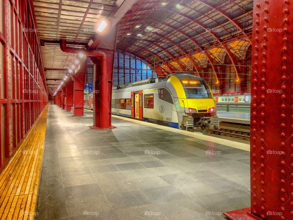 Antwerp central station in Antwerp, Belgium, as seen from the inside on the first or top platform with a train waiting on the rails at the platform, showing the structure of the old glass roof.