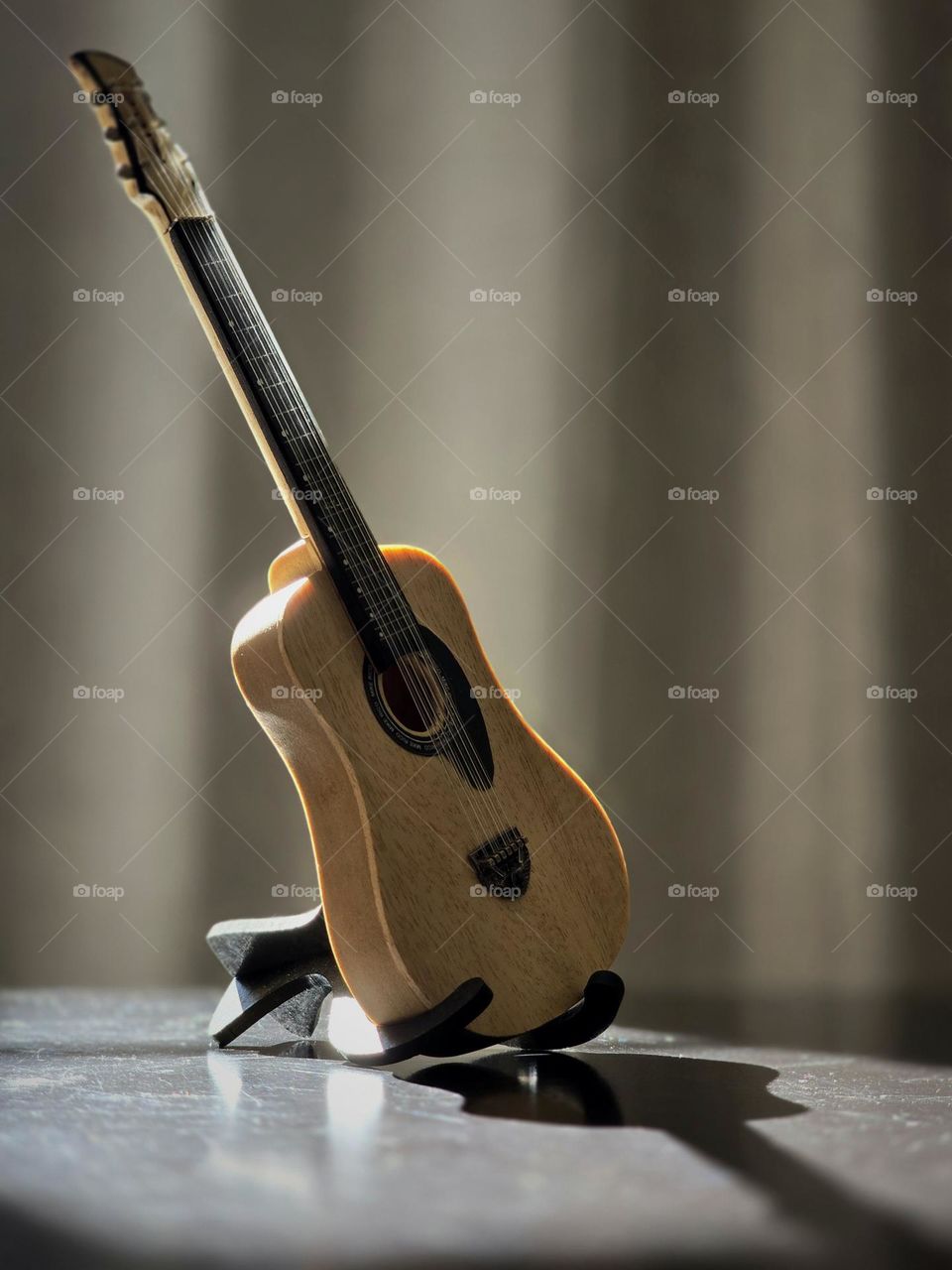 Small collection guitar placed on a table while receiving sunlight on it.