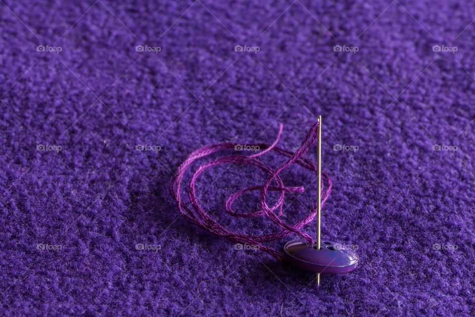 Sewing a button with purple needle and thread