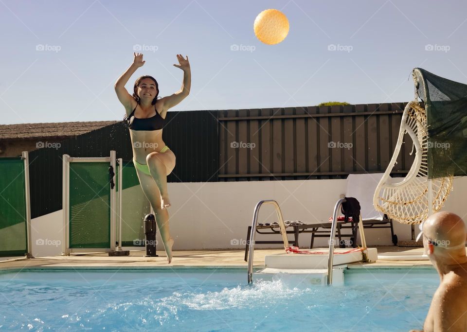 Jumping into the pool to play with a ball