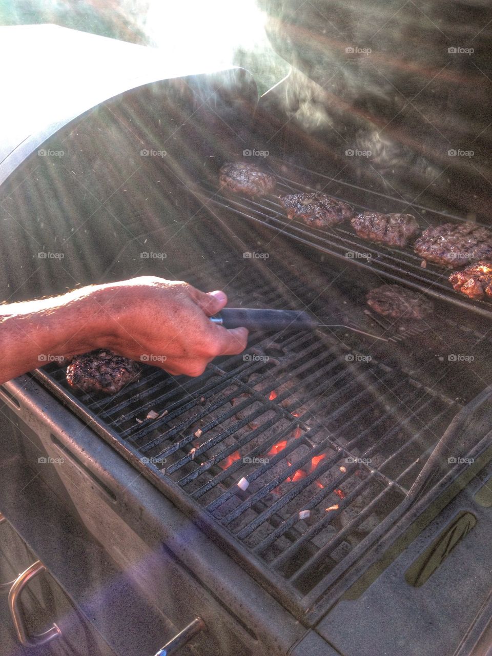 Flipping patties. Man flipping burgers on the grill
