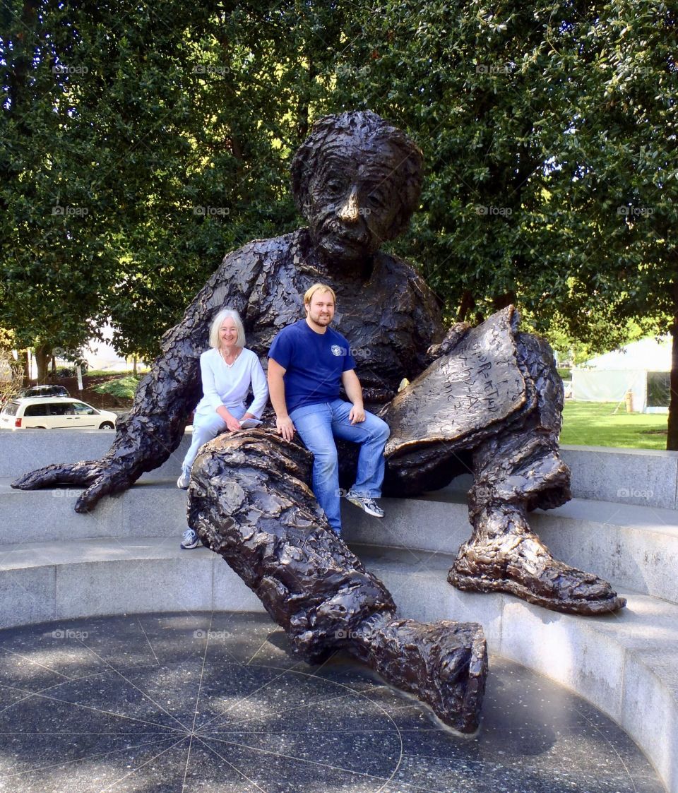 Man and woman sitting in the lap of Einstein statue