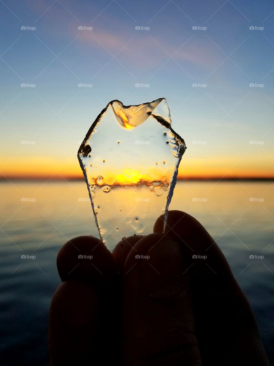 Person holding glass against calm sea