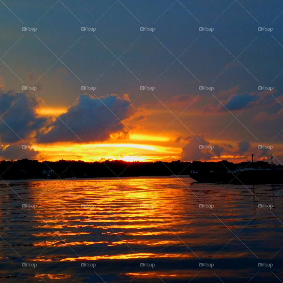 Scenic view of lake against dramatic sky at sunset