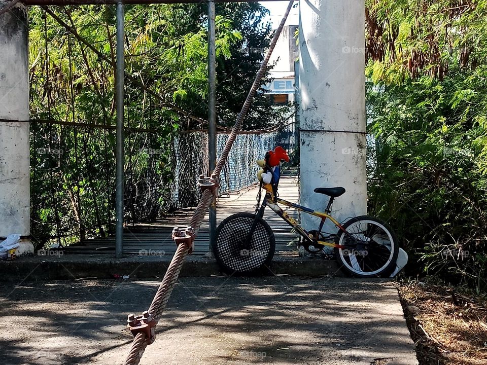 A bicycle left by the entrance of a wood bridge