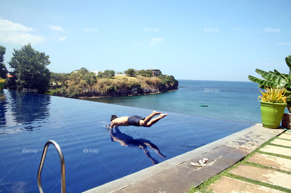 Man diving in infinity pool with an overlooking view