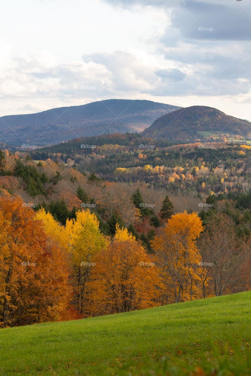 A picturesque mountain scene with bright colorful trees during autumn in New England.
